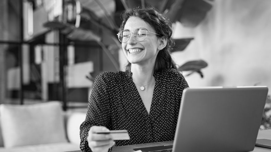 A person laughing while holding their credit card at their desk