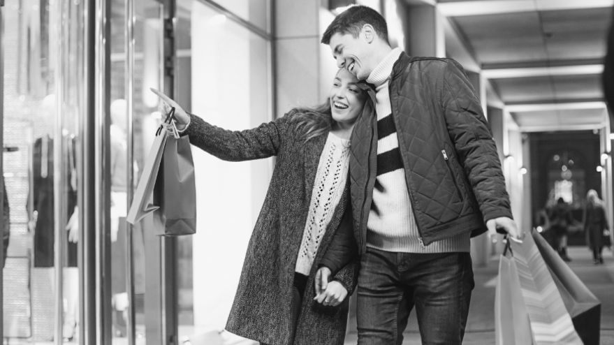 Couple laughing and holding hands while doing Black Friday shopping