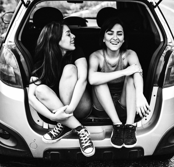 Two girls sitting in the boot of a new car