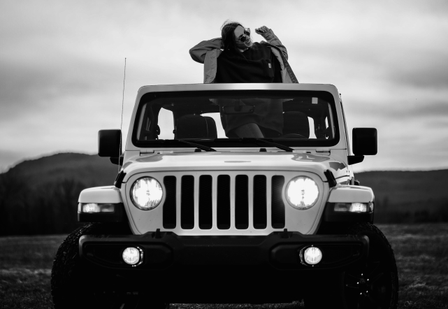 young woman standing up in a convertible jeep