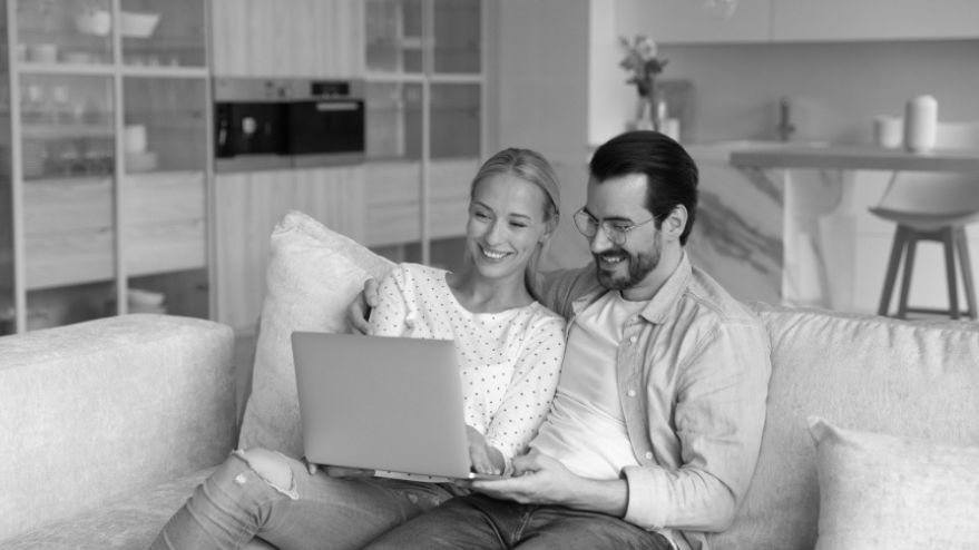 Couple sitting on a couch together looking at their laptop