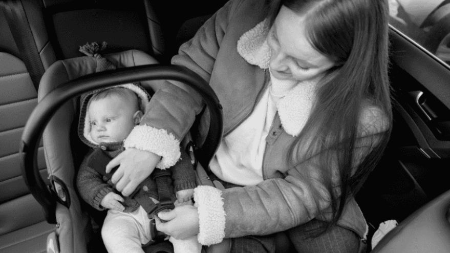 A parent carefully strapping an infant into a child car seat