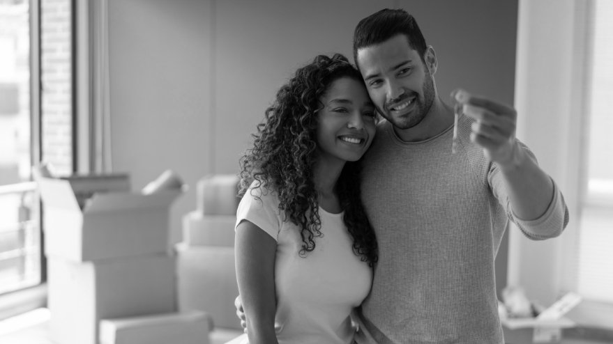 Couple hugging holding up a house key after drawing down their mortgage