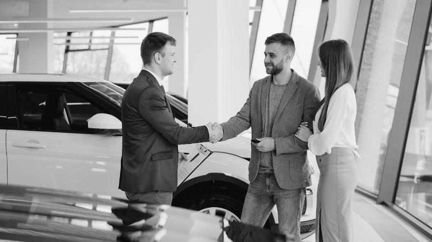 Couple talking to a salesman in a car showroom