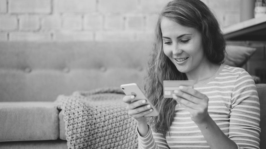 woman holding her phone as well as a credit card