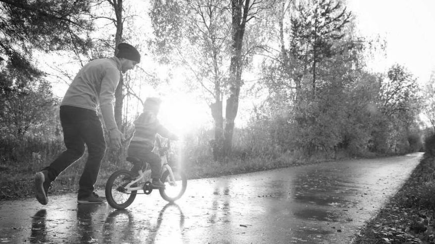 father showing child how to ride a new bike